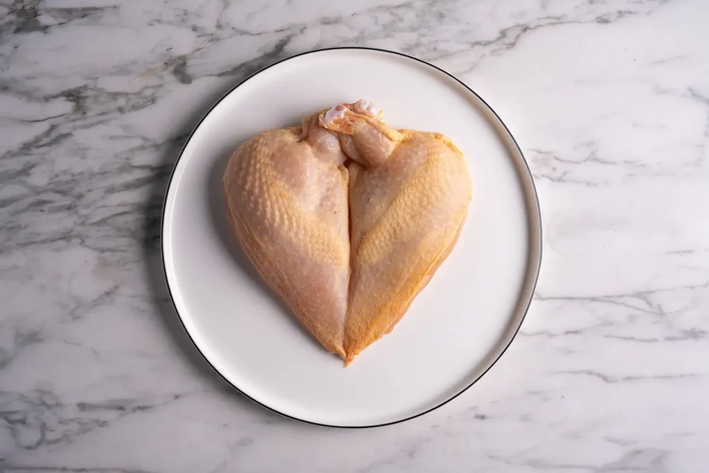 Rohes Hühnerfilet auf weißem Teller – Galeriebild 2/2 – Schader Fleisch – Produkte