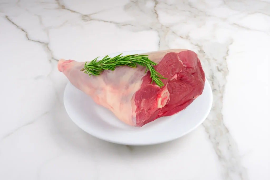 Schafschlögel auf weißem Teller, Marmorplatte im Hintergrund – Galeriebild 2/2 – Schader Fleisch – Produkte