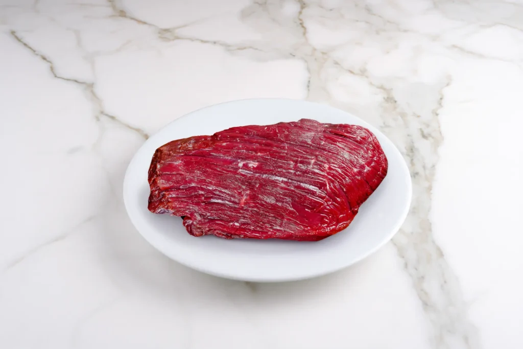 Wildfleisch auf weißem Teller, Marmorplatte im Hintergrund – Galeriebild 2/2 – Schader Fleisch – Produkte